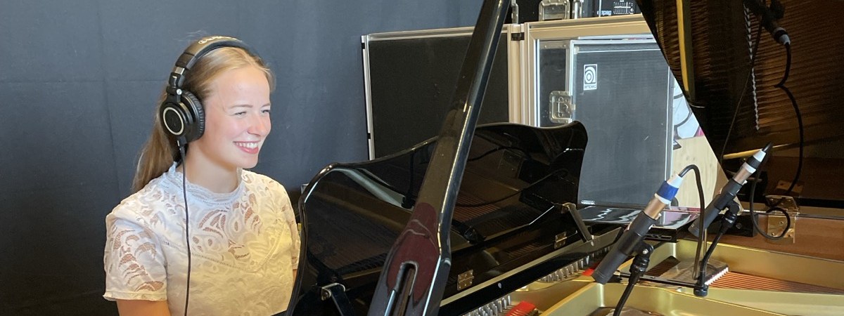 Studio-opname bij Popschool Your Song, leerling met koptelefoon aan de vleugel