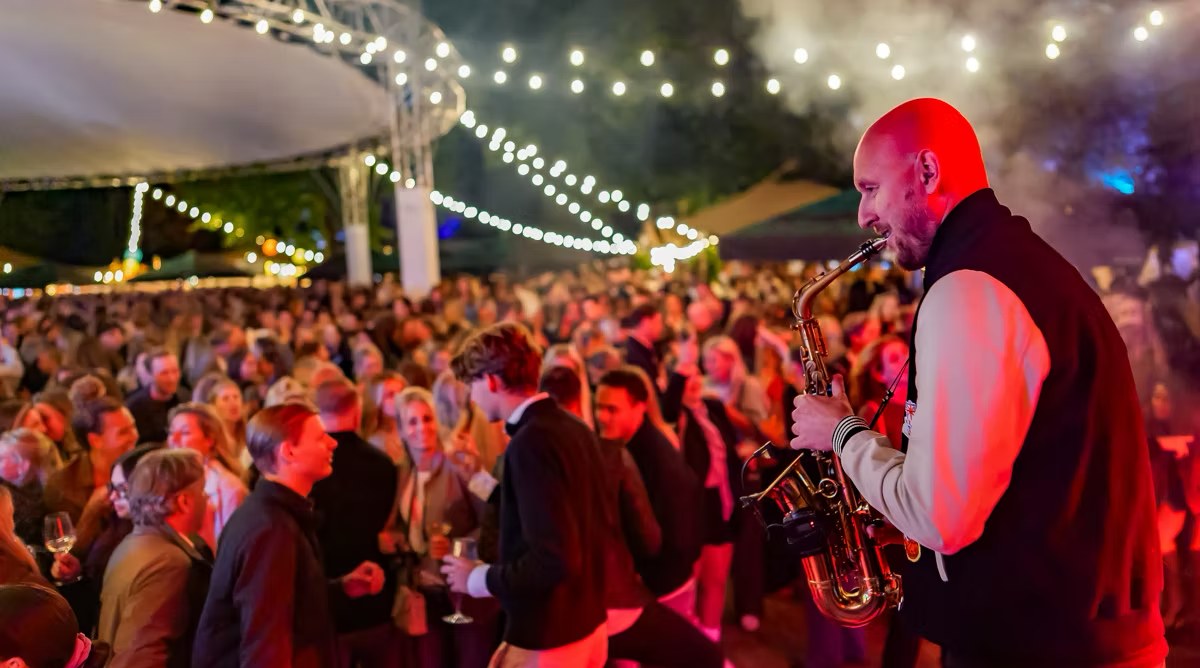Docent van Popschool Your Song speelt saxofoon voor een vol festivalpubliek
